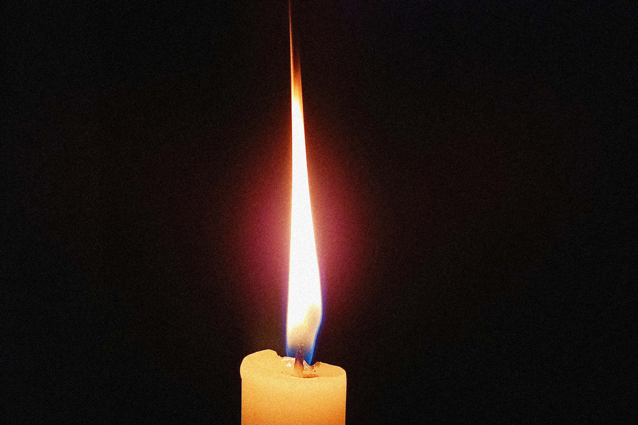 Eine angezündete Kerze in der Dunkelheit