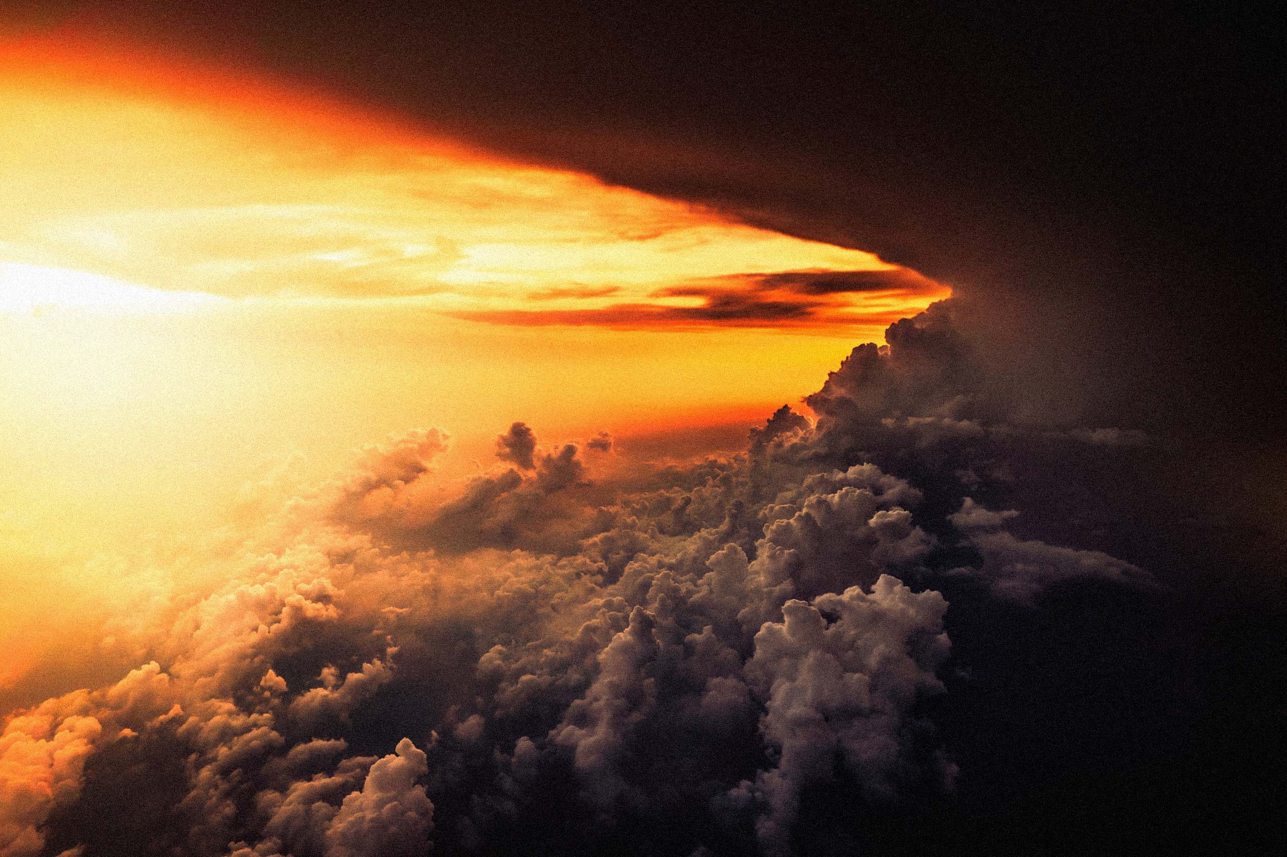 Ein orange-gelbfarbener Sonnenuntergang links und rechts ziehen sehr dunkle Wolken auf oder ab